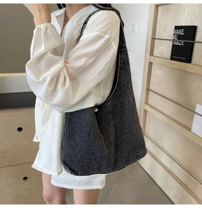 Détail du sac hobo en denim délavé avec boucle argentée et texture vintage sobre