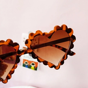 Détail de lunettes de soleil cœur pour enfants avec bordure ondulée en écaille