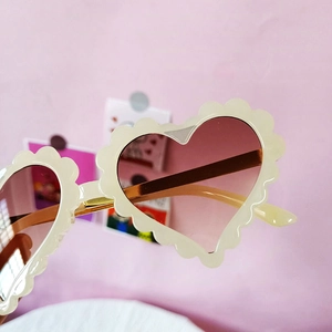 Détail de lunettes de soleil cœur blanches pour enfants avec verres dégradés roses