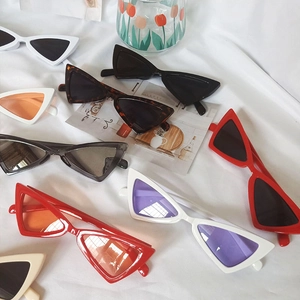 Gros plan de lunettes de soleil œil de chat rétro en plusieurs couleurs sur tissu blanc