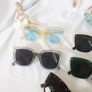 Detailed flat lay of oversized square sunglasses in assorted colors on soft white fabric