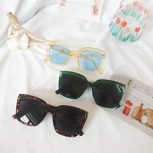Close-up of oversized square sunglasses in yellow, green, and leopard print on white cloth