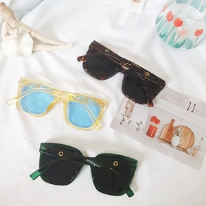 Three pairs of stylish oversized square sunglasses with gold rivet details on white fabric