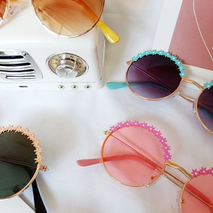 Vue à plat de lunettes de soleil fleurs pour enfants sur fond texturé blanc
