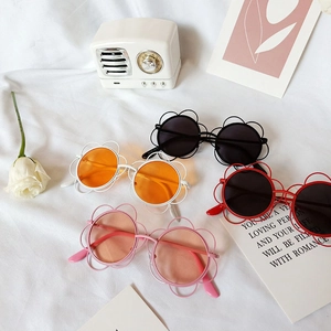 Flat lay of flower-shaped children's sunglasses in black, orange, red, and pink