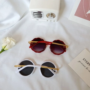 Petal-shaped children's sunglasses with metal temples on elegant white fabric