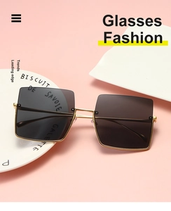 Detail of square oversized sunglasses with gold metal frame on white ceramic display