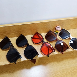 Collection of retro square sunglasses in black, orange, and white frames on a display stand