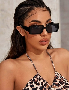 Detailed view of fashion square black sunglasses with dark lenses on a female model