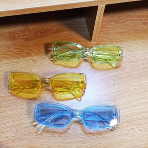 Three pairs of vintage candy-colored square frame sunglasses on a wooden surface