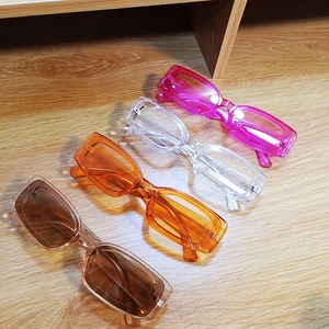 Set of four retro candy-colored rectangular transparent sunglasses on a wooden surface