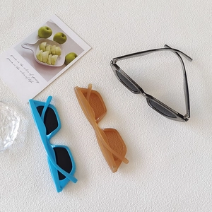 Three pairs of retro cat-eye sunglasses in blue, amber, and black resin frames