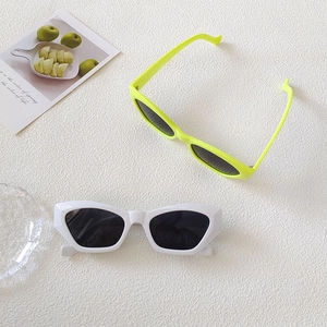 Flat lay of modern white and neon yellow cat-eye sunglasses on a textured surface