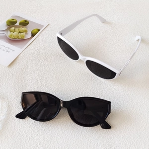 Détail de lunettes de soleil œil-de-chat ovales tendance en noir et blanc sur tissu