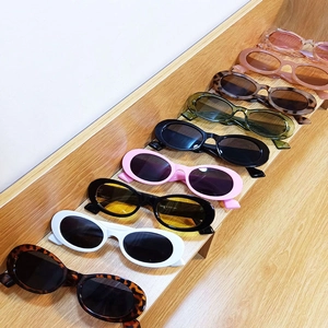 Retro oval sunglasses in various candy colors displayed on a wooden stand