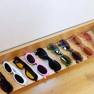 Detailed display of colorful retro oval sunglasses in various candy tones on a wood stand