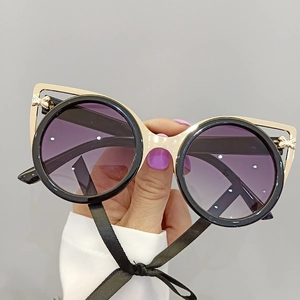 Detail of round sunglasses with golden bow accents and purple gradient lenses