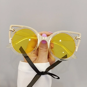 Close-up of cat-eye sunglasses with yellow lenses and metallic bow accent on the frame
