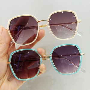 Close-up of stylish oversized kids sunglasses in beige and teal with gold metal frames