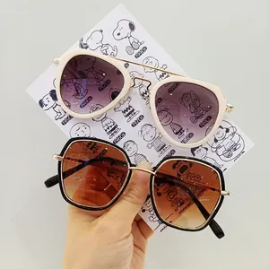 Detail of oversized kids sunglasses with metal bridge and gradient lenses held by hand