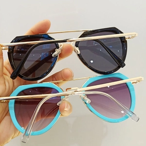 Close-up of black and blue oversized sunglasses with gold metal double bridge design