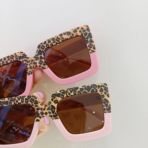 Detail showing two pairs of square leopard print and pink two-tone kids sunglasses