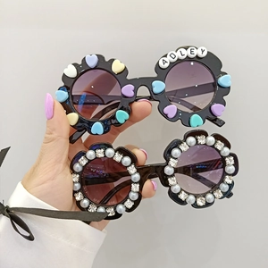 Détail de lunettes de soleil enfant en forme de fleur avec perles cœur et strass