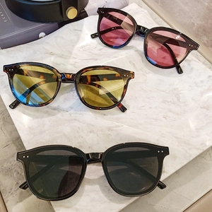Three pairs of vintage round sunglasses in black, tortoise, and purple on marble