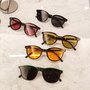 Five pairs of trendy oversized sunglasses in various lens colors on white marble surface