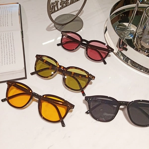 Flat lay of trendy sunglasses in pink, yellow, orange, and black on marble surface