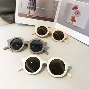 Three pairs of vintage round kids sunglasses in matte beige and olive on art magazine