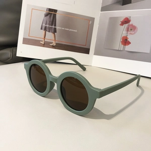 Detail shot of vintage dark green round sunglasses with brown lenses on a magazine background
