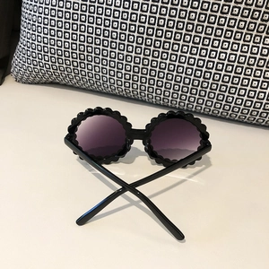 Detail of round wave-edge sunglasses frame with black finish and purple gradient lenses