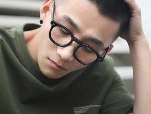 Detail of black full-rim glasses frame with silver rivets on a male model profile view