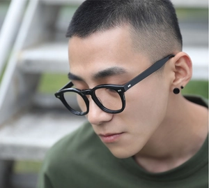 Close-up of black round anti-blue light glasses with metal rivets worn by a model