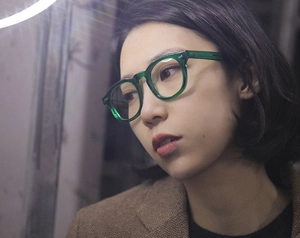 Model wearing translucent green round eyeglass frames showing fit and retro style