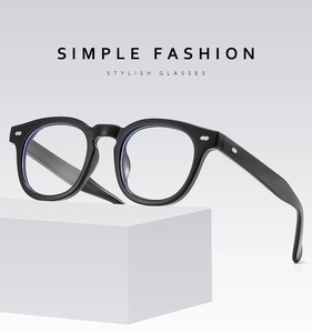 Detail of black anti-blue light glasses with metal rivets on a minimalist white stand