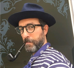 Détail d'une monture de lunettes noire et d'un foulard bleu sur un modèle masculin