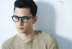 Détail d'une monture de lunettes ronde bleu foncé avec des rivets argentés à trois points
