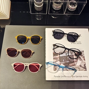 Flat lay of vintage small frame sunglasses with rivets and assorted fashion eyeglasses