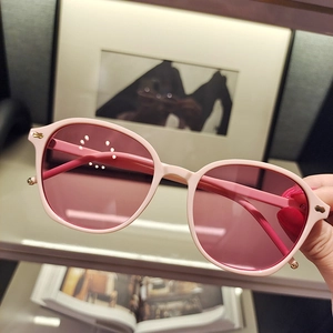 Close-up of pink sunglasses with small frames and golden metal hinge detail