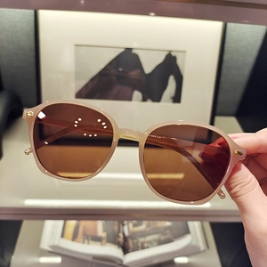 Close-up of beige rectangular sunglasses featuring brown gradient lenses and gold studs