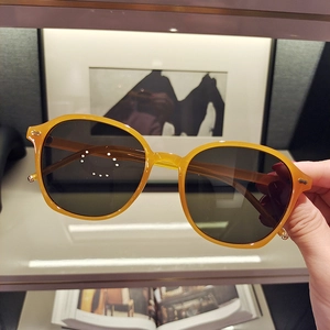 Detail of amber yellow resin sunglasses frame with dark lenses and gold rivet accents