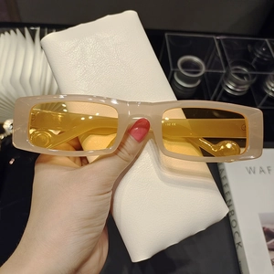 Detail of retro rectangular cream sunglasses with yellow lenses and Y2K aesthetic style