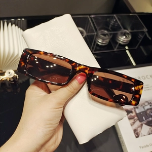 Close-up of tortoise shell rectangle sunglasses with brown lenses and leather case