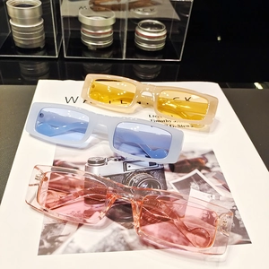 Detailed view of three rectangular sunglasses in yellow, blue and pink colors on a magazine
