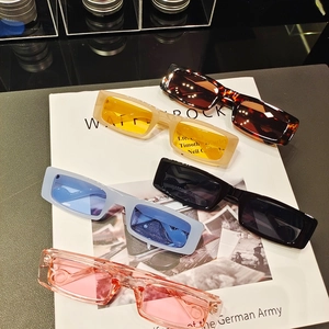 Five pairs of trendy rectangular sunglasses in various colors displayed on a white magazine
