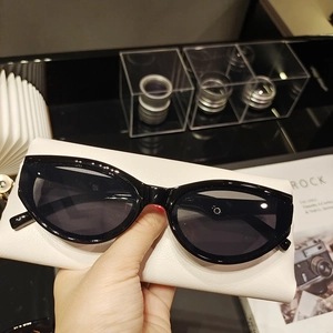 Close-up of vintage black cat-eye sunglasses with a minimalist white leather case