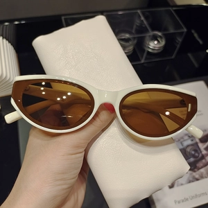 Close-up of white cat eye sunglasses with brown lenses and leather storage pouch