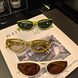 Three pairs of vintage cat-eye sunglasses in green and cream on a fashion magazine